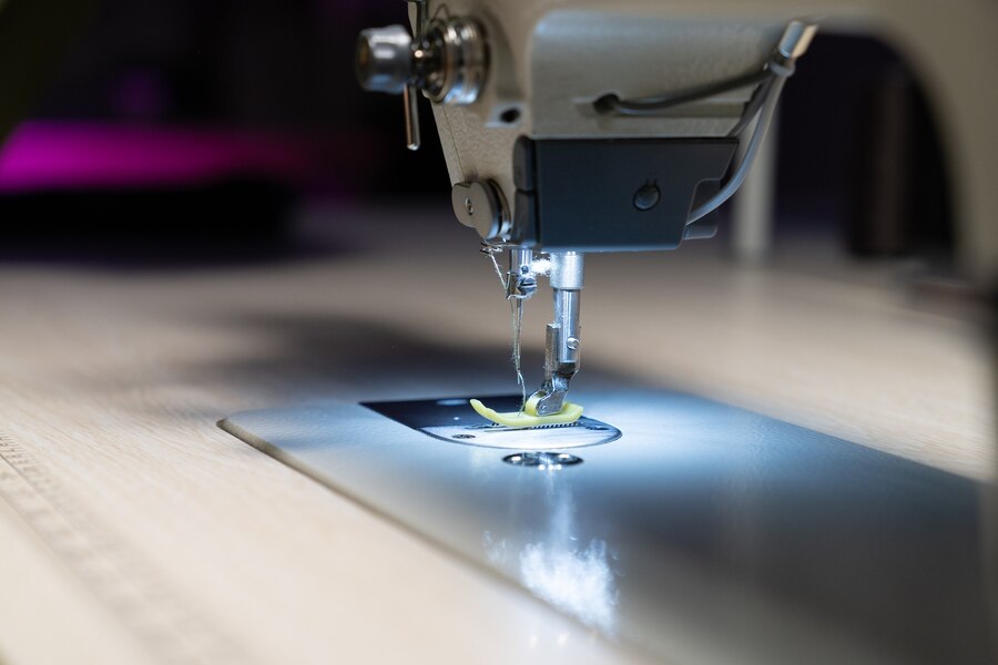 closeup-sewing-machine-needle-cloth-seamstress-workplace-garment-industry